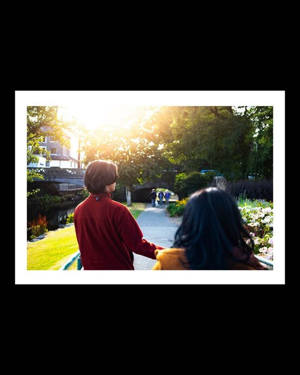 Two people on a bridge, looking the same way