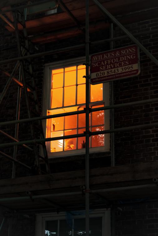 One lit window behind the scaffolding